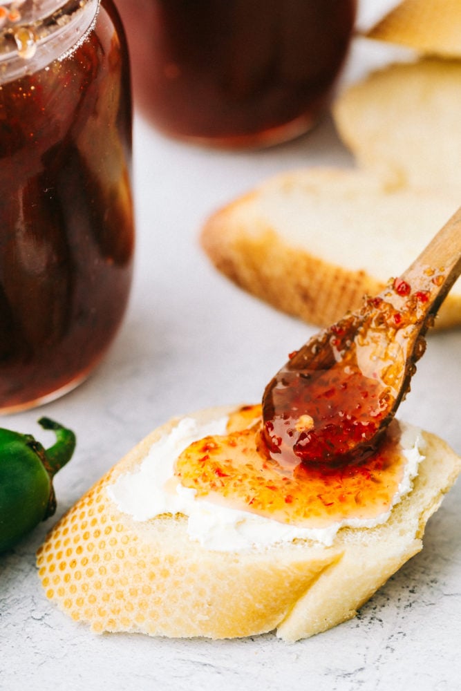 Homemade Jalapeño Jelly is a perfect sweet and spicy combination you will want to slather on everything. It will become a staple in your fridge or freezer from now on! Spreading jalapeno jelly of bread with butter.