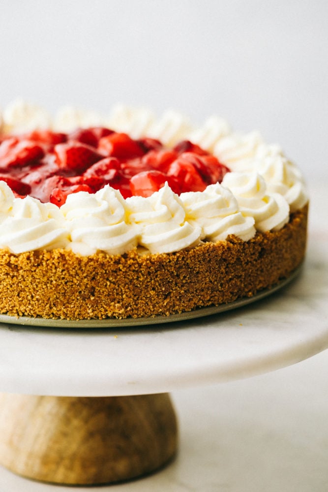 No Bake Cheesecake is so creamy, luxurious, and surprisingly easy to make from scratch at home.ย Top it with whipped cream and fresh fruit and it will be a huge hit that everyone will obsess over! Close up on finished no bake cheesecake decorated with whipped cream and strawberries.