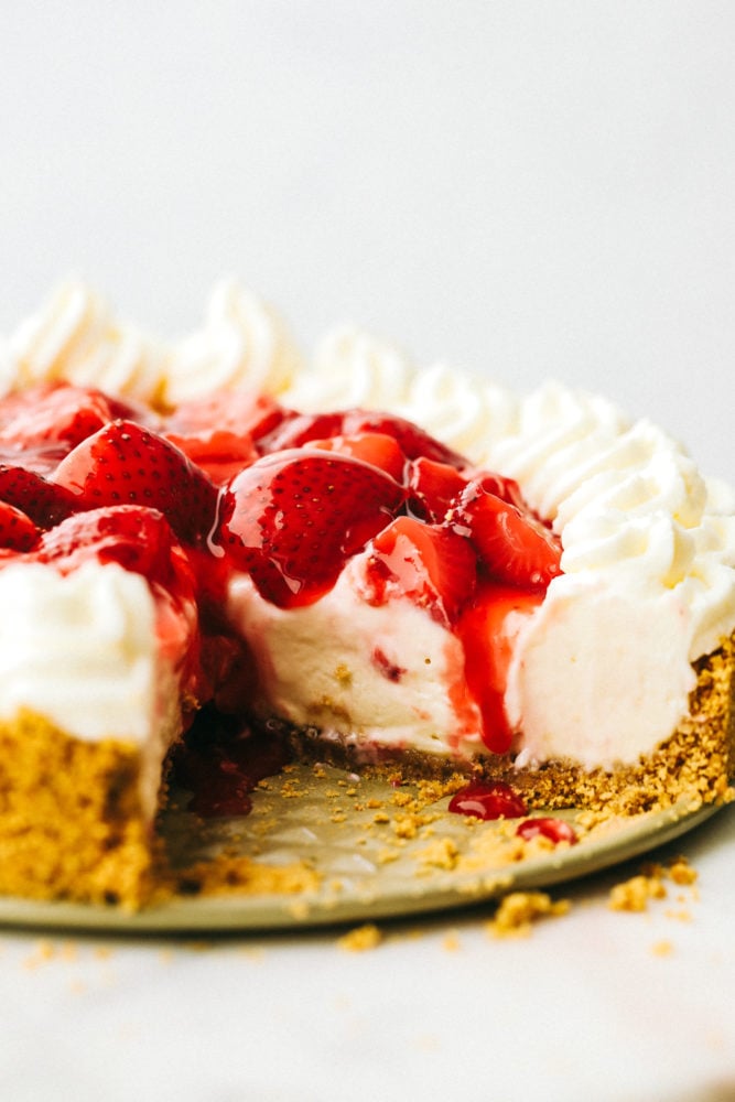 No Bake Cheesecake is so creamy, luxurious, and surprisingly easy to make from scratch at home.ย Top it with whipped cream and fresh fruit and it will be a huge hit that everyone will obsess over! Close up on a no bake cheesecake with one slice missing.
