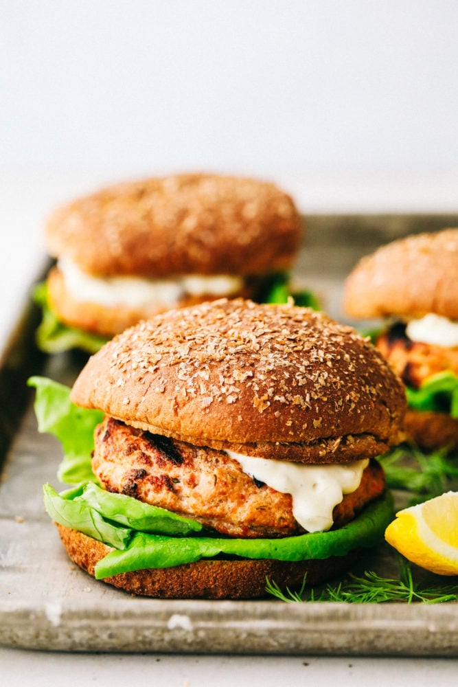 Salmon Burgers are light and tasty burgers that are easy to make ahead and enjoy all summer!ย The homemade salmon patty is flavorful and quick and easy to grill! Finished salmon burgers on a tray.