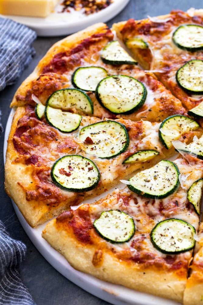 This easy zucchini pizza recipe is the perfect vegetarian meal when you're craving a slice. Fresh dough is topped with a savory red sauce, mozzarella cheese, and thin slices of zucchini. The pie is baked until the crust is crispy and cheese is hot and bubbly. Pizza pie thats been cut into slices