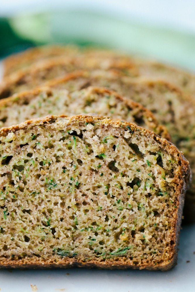 You better believe I count down to zucchini season so I know when I can make this delicious Zucchini Bread! It’s moist, perfectly spiced, and loaded with the best flavor and a hint of veggies! Photo facing the zucchini bread sliced and laying back.