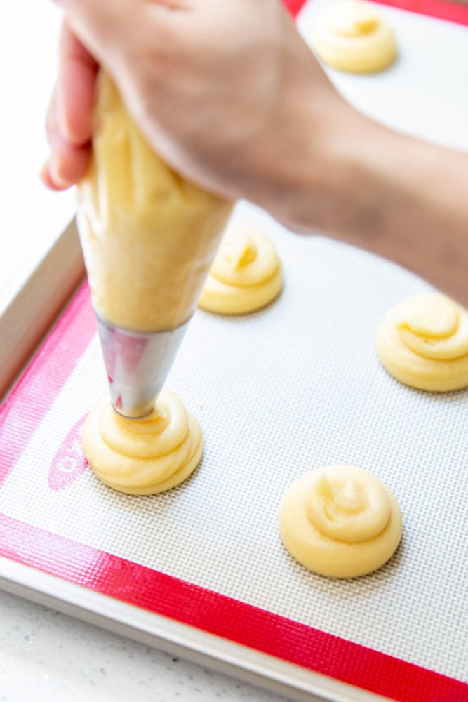 Cream puffs filled with simple vanilla whipped cream and covered in a dusting of powdered sugar are a classic dessert. But once youโve mastered the recipe for the cream puff shell, it can be customized with all sorts of delicious filling to your heartโs desire! Piping choux pastry for baking