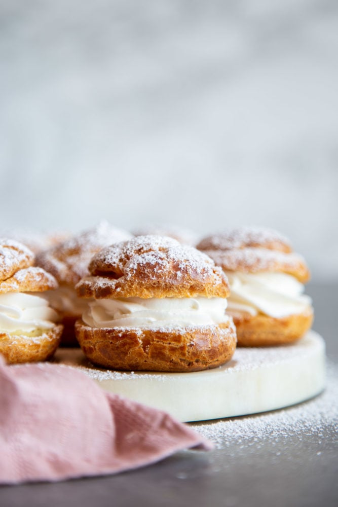 Cream puffs filled with simple vanilla whipped cream and covered in a dusting of powdered sugar are a classic dessert. But once youโve mastered the recipe for the cream puff shell, it can be customized with all sorts of delicious filling to your heartโs desire! Cream puffs dusted with powdered sugar