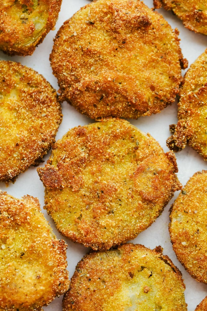 Fried Green Tomatoes are extremely popular sliced and fried crunchy bites of tangy green tomatoes. They are totally addictive and easy to make at home! View of finished fried green tomatoes on a tray.