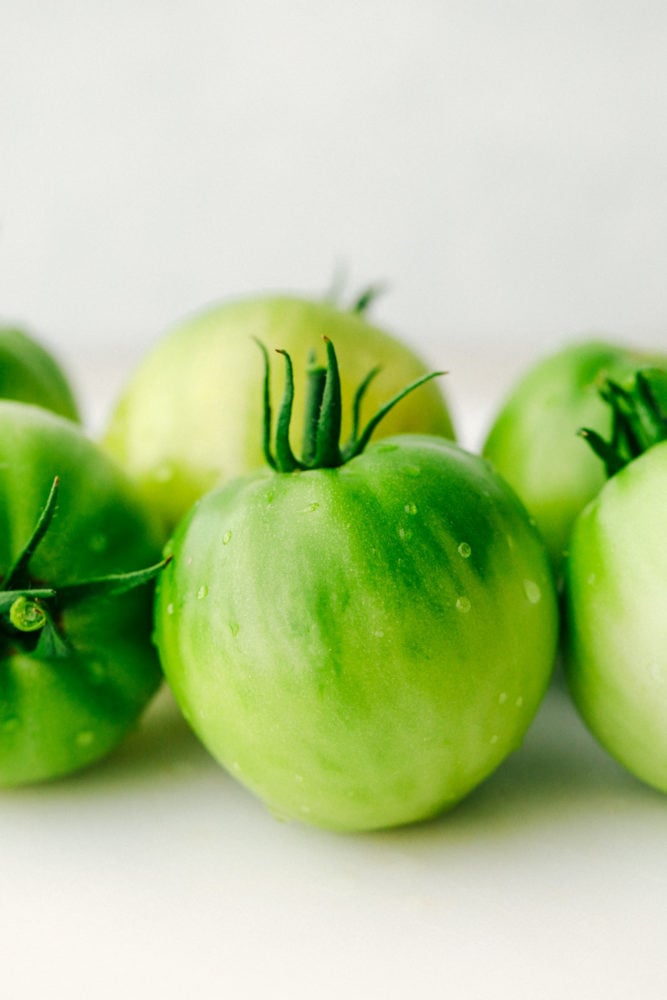 Fried Green Tomatoes are extremely popular sliced and fried crunchy bites of tangy green tomatoes. They are totally addictive and easy to make at home! Green tomatoes close up.