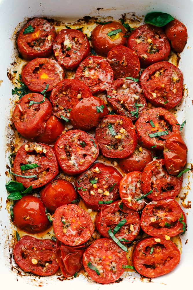 A sensational seasonal must have side dish, this is bursting with juicy savory flavor. These roasted and seared to perfection tomatoes are a perfect quick go to. Topped with cheesy goodness and fresh basil this is sure to please any crowd. Roasted tomatoes sliced in a pan topped with basil and cheese