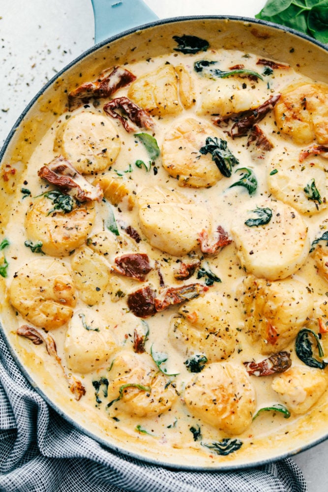 Creamy tuscan garlic scallops are infused in a savory garlic sauce that is absolutely to die for! Easy to make and filled to the brim with flavor, this is a MUST-make dinner for busy weeknights! Creamy tuscan garlic scallops in a skillet.