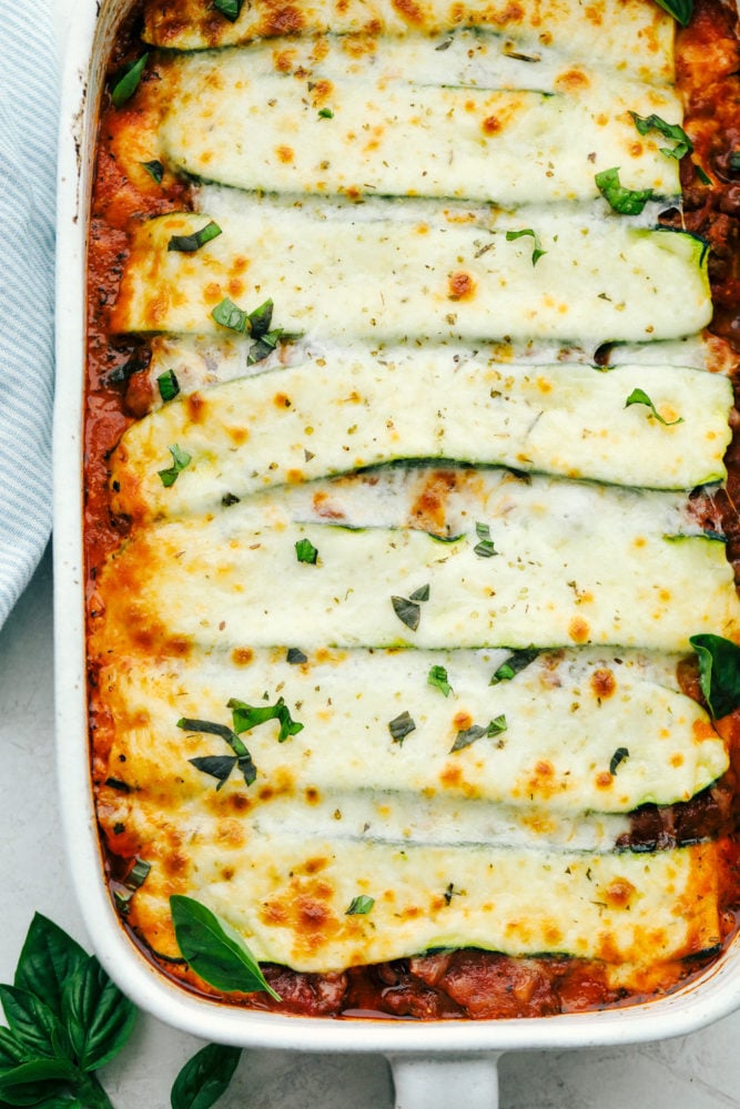 Zucchini Lasagna is a low-carb, gluten free twist on your favorite Italian comfort food. This is an absolutely scrumptious way to use all that zucchini from your garden. Zucchini lasagna in a white casserole dish.
