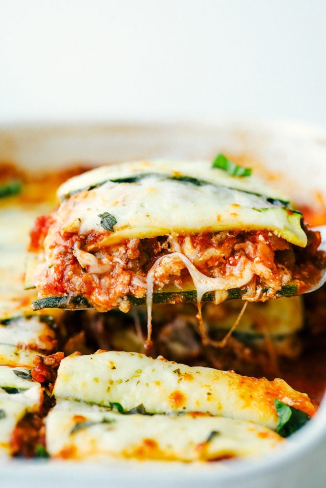 Zucchini Lasagna is a low-carb, gluten free twist on your favorite Italian comfort food. This is an absolutely scrumptious way to use all that zucchini from your garden. A photo of zucchini lasagna having a piece taken out of the casserole dish.