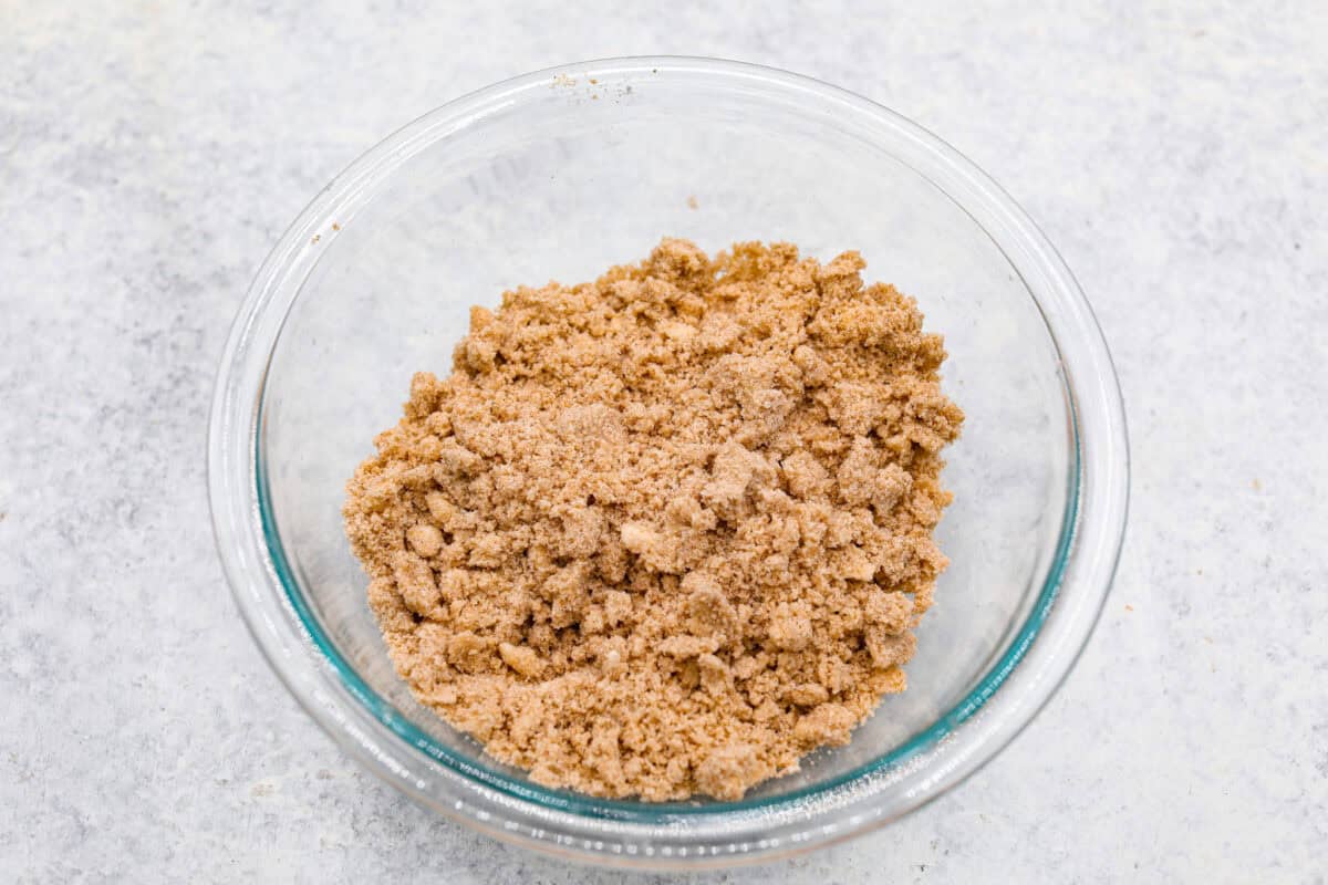This classic cinnamon coffee cake is loaded with decadent cinnamon sugar swirls and topped with crumbly cinnamon streusel. It's the perfect treat to share at any brunch, book club, or dessert for any night of the week. The warm, satisfying aroma will fill your heart and your home! Overhead shot of the streusel topping mixed with the butter.