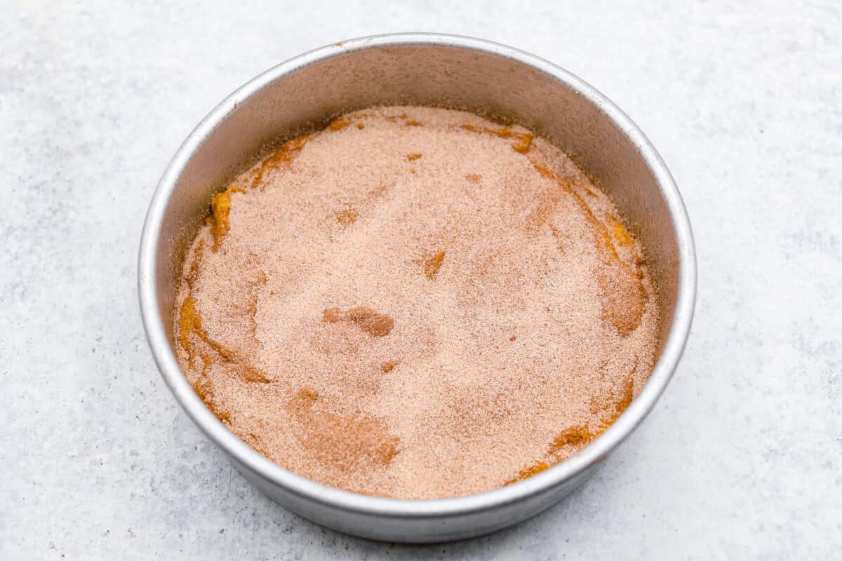This classic cinnamon coffee cake is loaded with decadent cinnamon sugar swirls and topped with crumbly cinnamon streusel. It's the perfect treat to share at any brunch, book club, or dessert for any night of the week. The warm, satisfying aroma will fill your heart and your home! Overhead shot of the bottom layer of the cake with cinnamon sugar swirl on top.