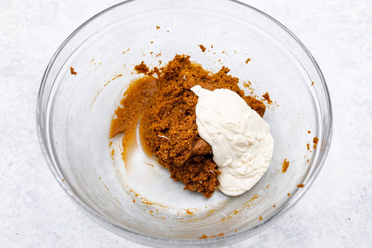 Pumpkin cream cheese truffles combine smooth cream cheese, pumpkin puree, crunchy graham cracker, and gingersnap crumbs, all dunked in sweet white chocolate. The best fall dessert. Overhead shot of cream cheese and crumb mixture with melted white chocolate chips.