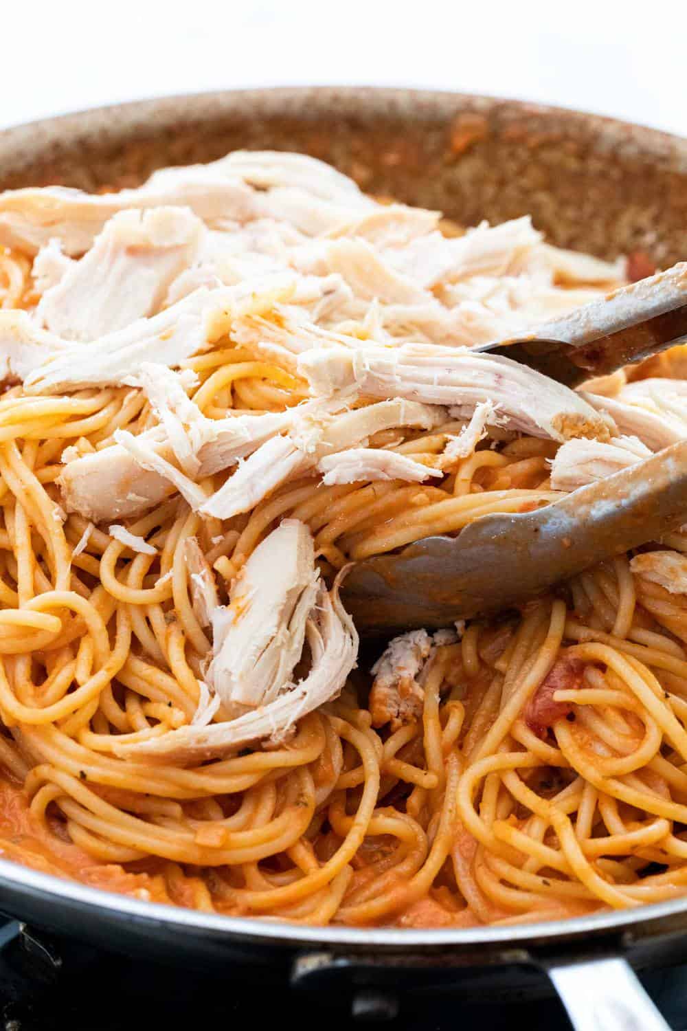 Baked chicken spaghetti is an easy dinner casserole to feed a family. Tender pieces of chicken tossed with tender noodles and a creamy tomato sauce. Shredded chicken on top of pasta