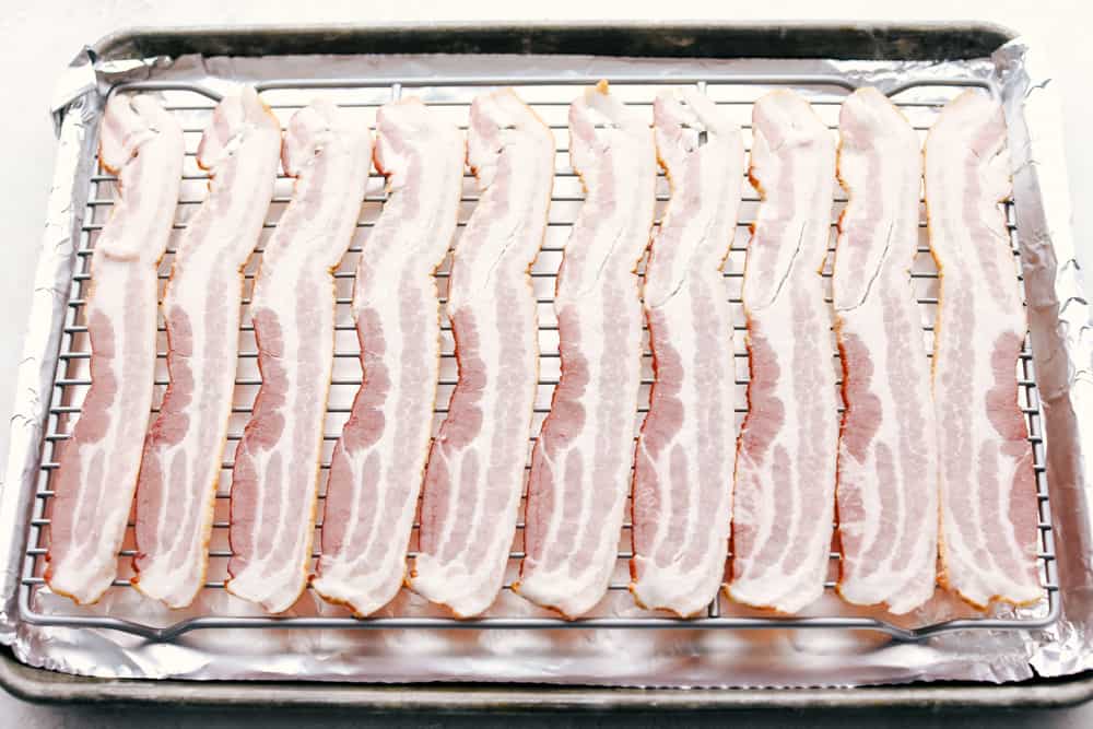 Everyone loves Bacon, and once you try baking it, you'll love it even more! It's just perfectly crisp, amazing flavor, and easy clean up. You will have bacon every morning! Raw Bacon on a lined cookie sheet getting ready to Bake