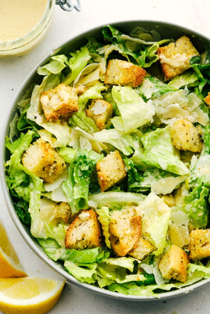 Fresh crisp romaine lettuce, large shaved parmesan cheese, crunchy croutons and a creamy dressing make this Caesar Salad a must make. Caesar salad goes with so many things and it's always a family favorite. Crispy, light and fresh Caesar Salad with homemade dressing and croutons.