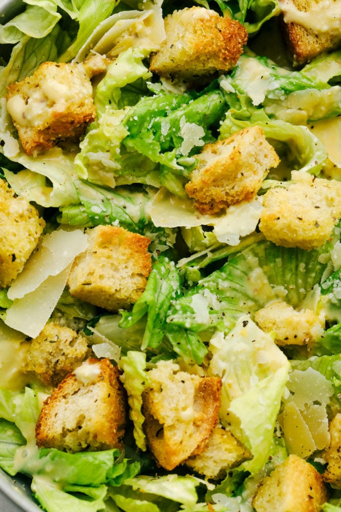 Fresh crisp romaine lettuce, large shaved parmesan cheese, crunchy croutons and a creamy dressing make this Caesar Salad a must make. Caesar salad goes with so many things and it's always a family favorite. Crispy, light and fresh Caesar Salad with homemade dressing and croutons.