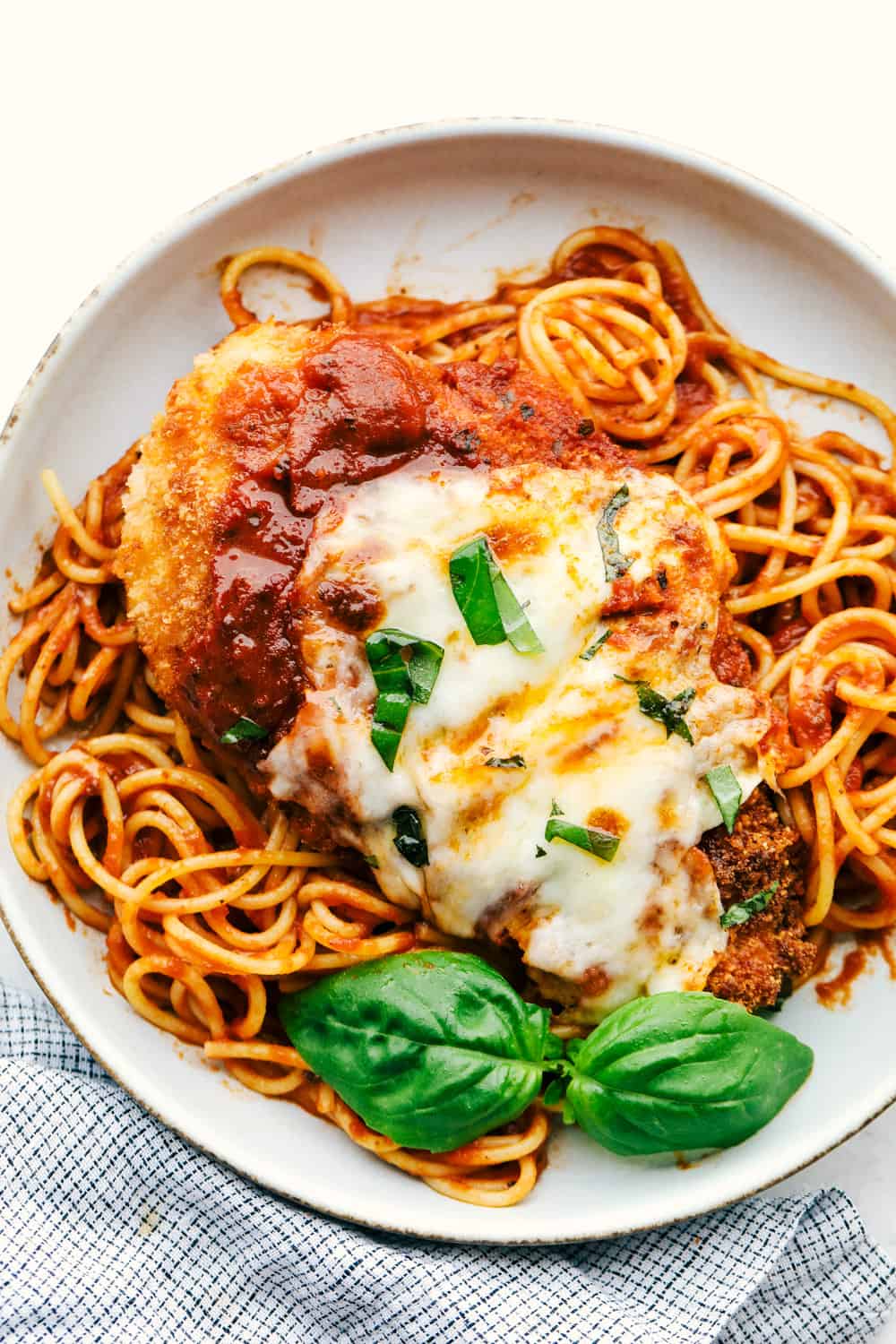 Sharing my best Chicken Parmesan recipe with you today with tender, juicy chicken that is full of flavor and a ย dinner everyone will love! Parmesan chicken on a bed of spaghetti with marinara sauce.