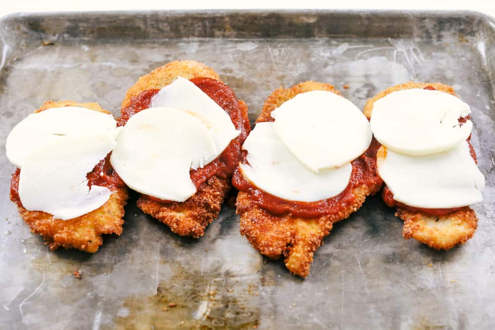 Sharing my best Chicken Parmesan recipe with you today with tender, juicy chicken that is full of flavor and a ย dinner everyone will love! Fried chicken parmesan with marinara and cheese on a sheet pan.