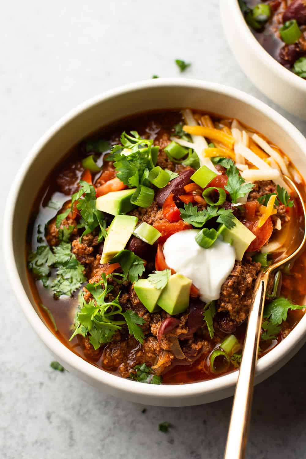 Instant Pot Chili is simple to make and hearty. The electric pressure cooker builds amazing flavors in a short time, and everyone will love loading up their bowls with their favorite toppings! Instant Pot chili in a bowl with a gold spoon