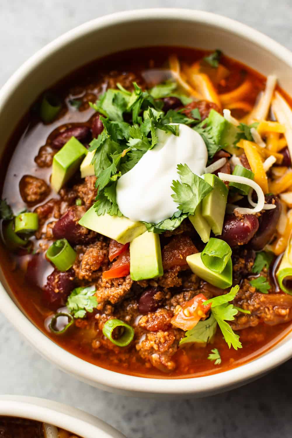 Instant Pot Chili is simple to make and hearty. The electric pressure cooker builds amazing flavors in a short time, and everyone will love loading up their bowls with their favorite toppings! close-up of a bowl of Instant Pot chili.