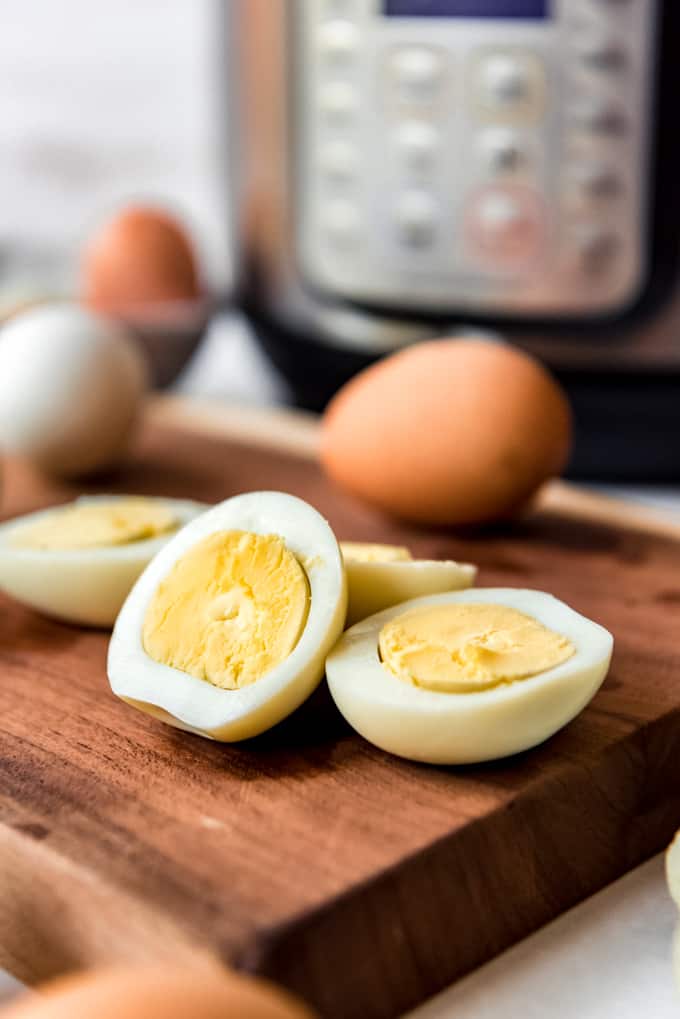 Instant Pot Hard Boiled Eggs are hands down the best thing to make in your electric pressure cooker! Not only do they turn out perfect every time, but they peel better than any other method! Sliced hard boiled eggs in front of an Instant Pot.