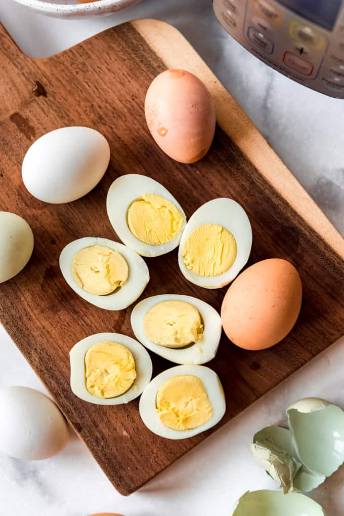 Instant Pot Hard Boiled Eggs are hands down the best thing to make in your electric pressure cooker! Not only do they turn out perfect every time, but they peel better than any other method! Sliced hard boiled eggs on a wooden cutting board.