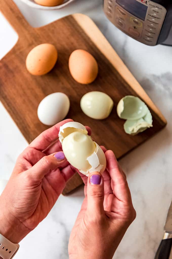 Instant Pot Hard Boiled Eggs are hands down the best thing to make in your electric pressure cooker! Not only do they turn out perfect every time, but they peel better than any other method! Hands holding a peeled hard boiled egg.