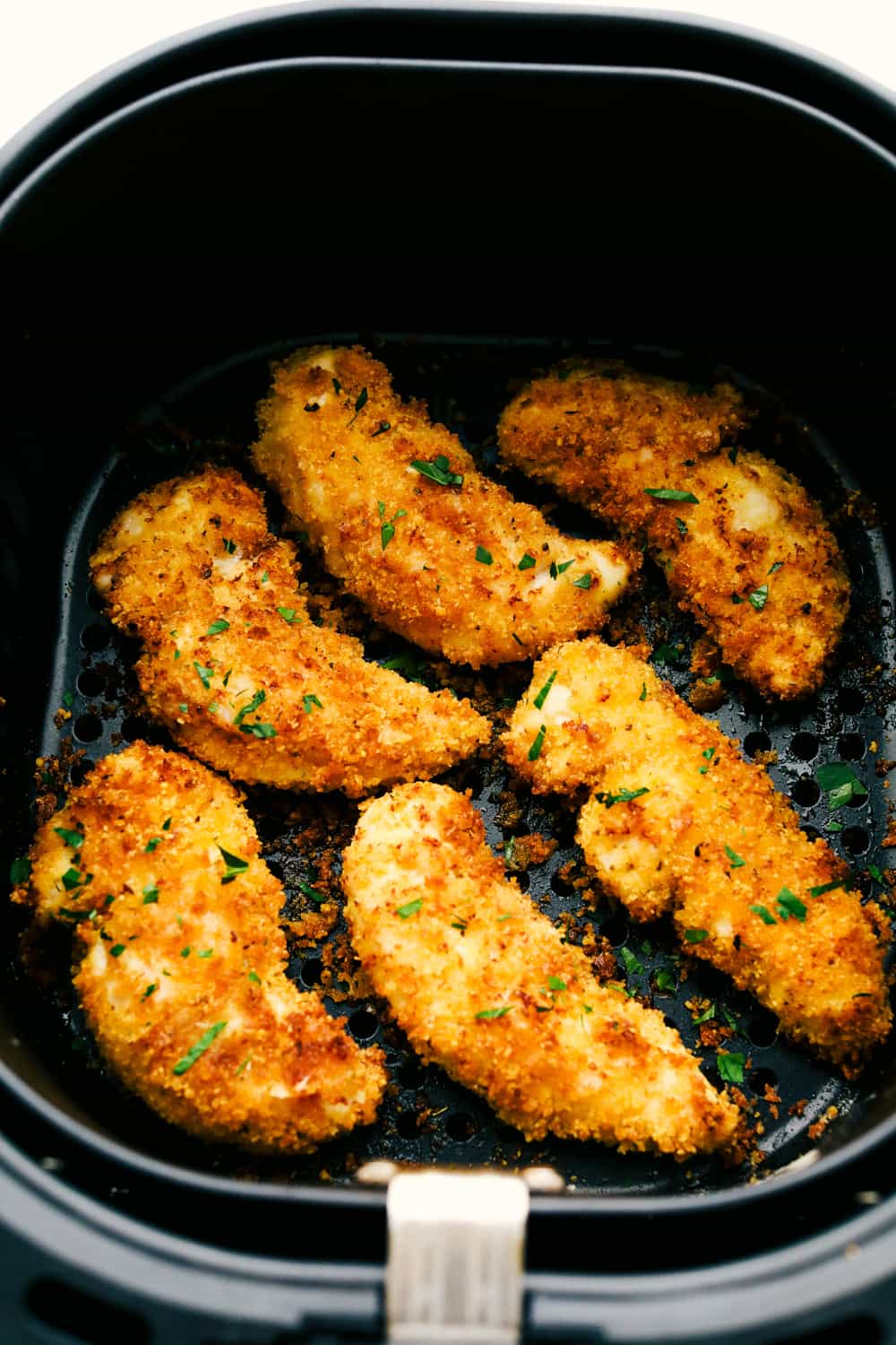 These air fryer chicken tenders are a lifesaver on crazy weeknights. Crispy, cheesy, and full of flavorโplus they cook up fast and my kidsย actuallyย ask for seconds. Total win! Breaded and cooked chicken in the air fryer basket.