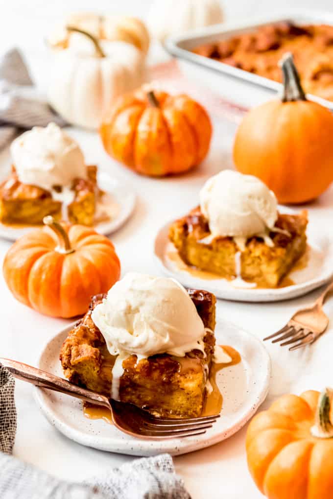 Pumpkin Bread Pudding is an easy and fantastic recipe that tastes like you have spent a lot of time putting it together when it really only takes minutes! Drizzle warm slices with caramel sauce and serve it with ice cream for a decadent dessert, or even enjoy it for breakfast like a baked french toast casserole! Slices of pumpkin bread pudding with ice cream on top.