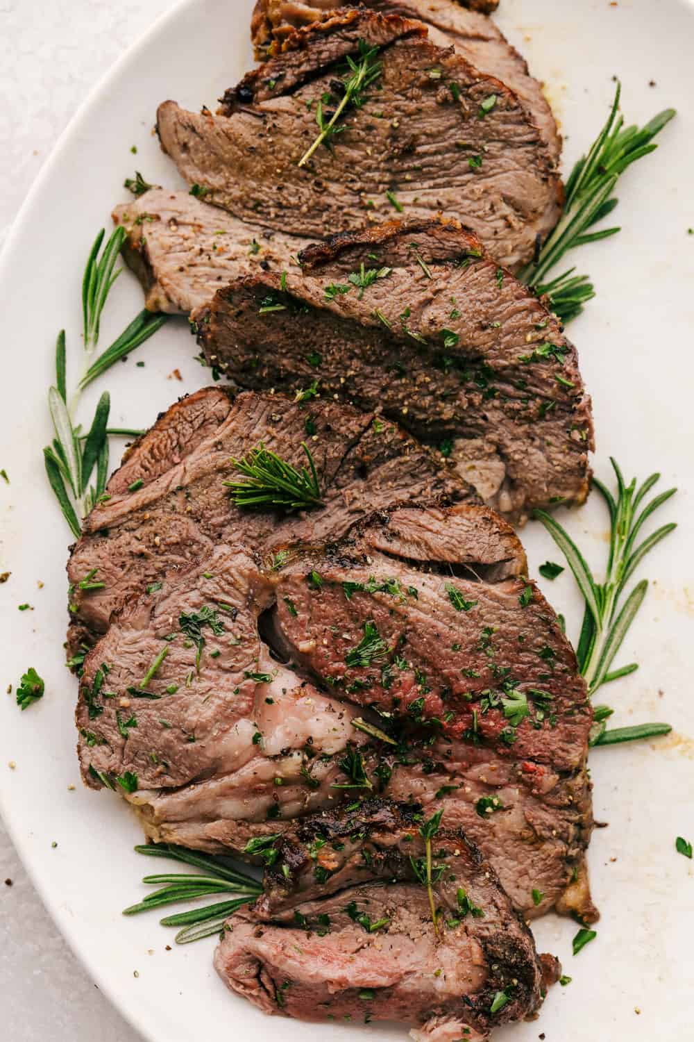 Savory Garlic Herb Crusted Roast Lamb is tender and succulent, perfect for any special occasion. The meat is tender and juicy and the crust gives it such a beautiful flavor. Perfection on a platter! Roasted Garlic Herb Crusted Lamb on a platter.