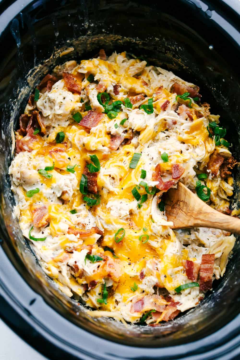 This slow cooker crack chicken (cheddar ranch chicken) is an addicting combination of chicken, cheese, bacon and ranch dressing. Cooking this in the slow cooker takes all the work out of it and makes it a super simple hearty dinner for busy days. Close up of creamy, rich and addicting Slow Cooker Crack Chicken with cheddar, bacon and ranch.