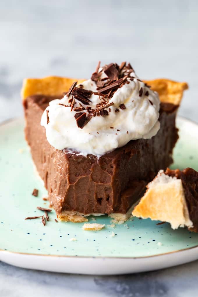 Chocolate Pie has an easy, homemade chocolate pudding that is the perfect pie filling! Smooth and creamy chocolate layered with sweet, vanilla whipped cream is the perfect dessert.ย Chocolate pie on a plate with a bite taken out of it.