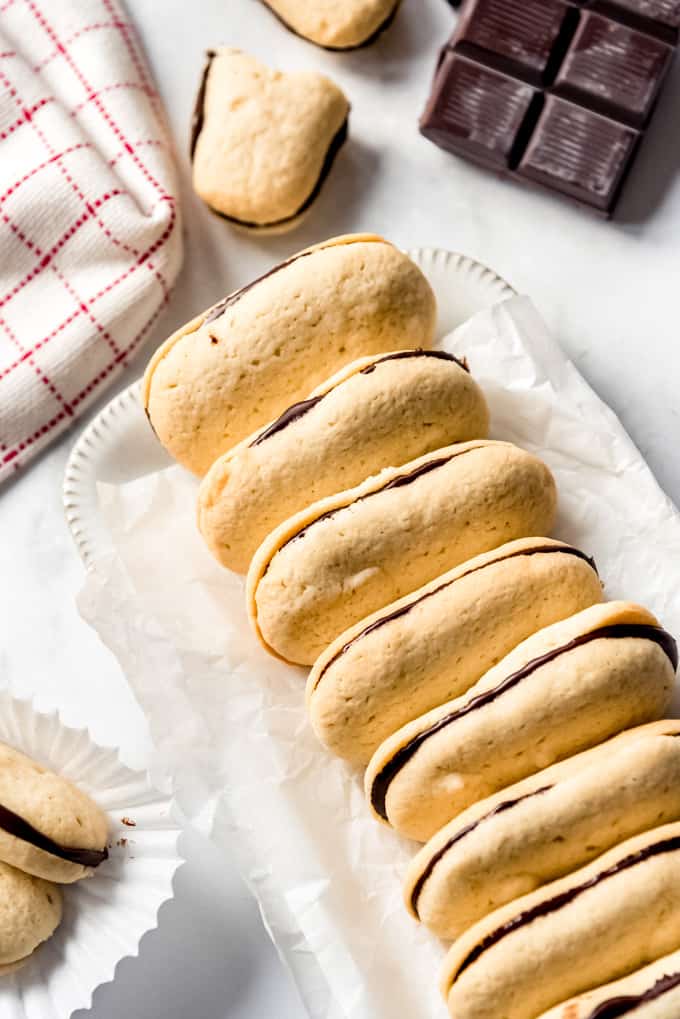 Homemade Milano Cookies have tender cookies with a nice crunch sandwiched around a layer of rich dark chocolate in the center! They taste even better than the store bought version! Milano cookies stacked together on a white dish.
