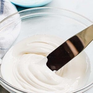 Royal icing in a glass bowl with a spreader.
