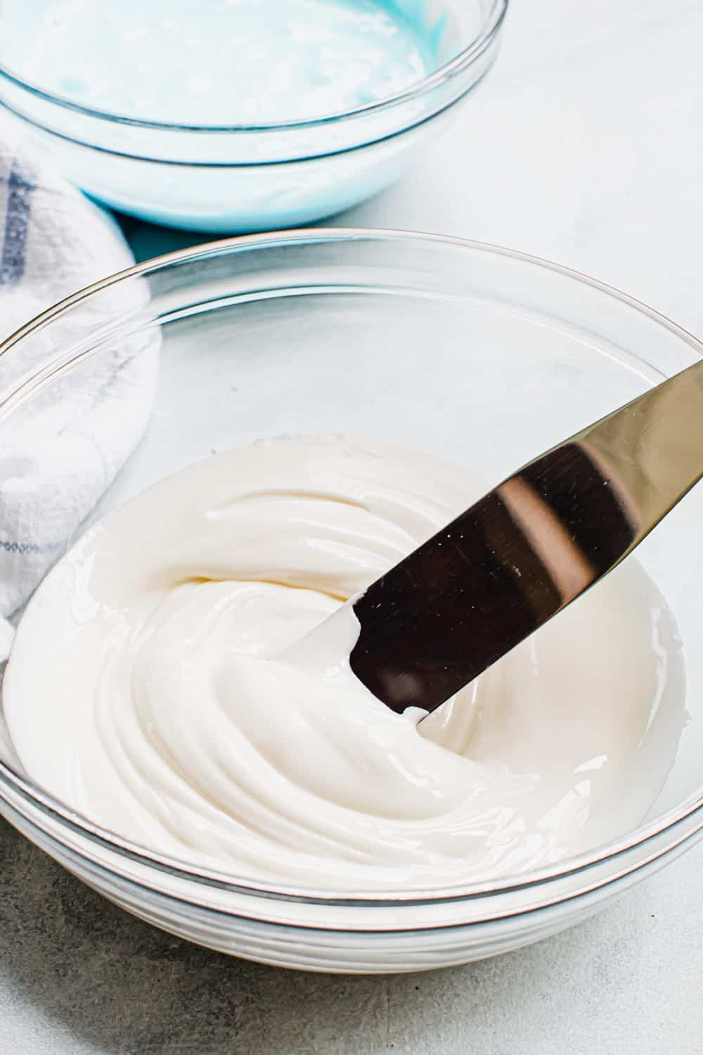 This classic and simple royal icing recipe is a cookie decorating staple with a smooth consistency that sets quickly without hardening too much. Made with meringue powder it has a delicious taste and a smooth texture that's perfect for flooding and piping cookies. Royal icing in a glass bowl with a spreader.