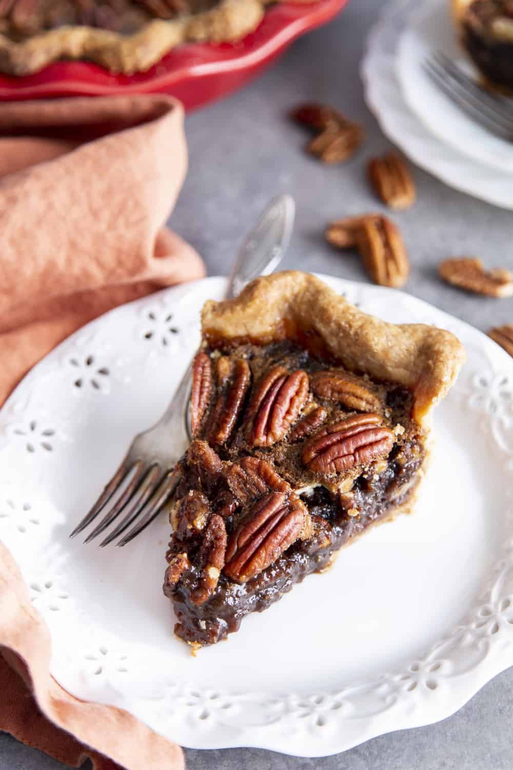 Amazing Decadent Pecan Pie is a rich, chewy, nutty, sweet, traditional holiday staple. For many the holidays aren't the holidays without this brilliant dessert on the table. This homemade delight is surprisingly super simple. You are going to love it! Decadent pie on a plate.