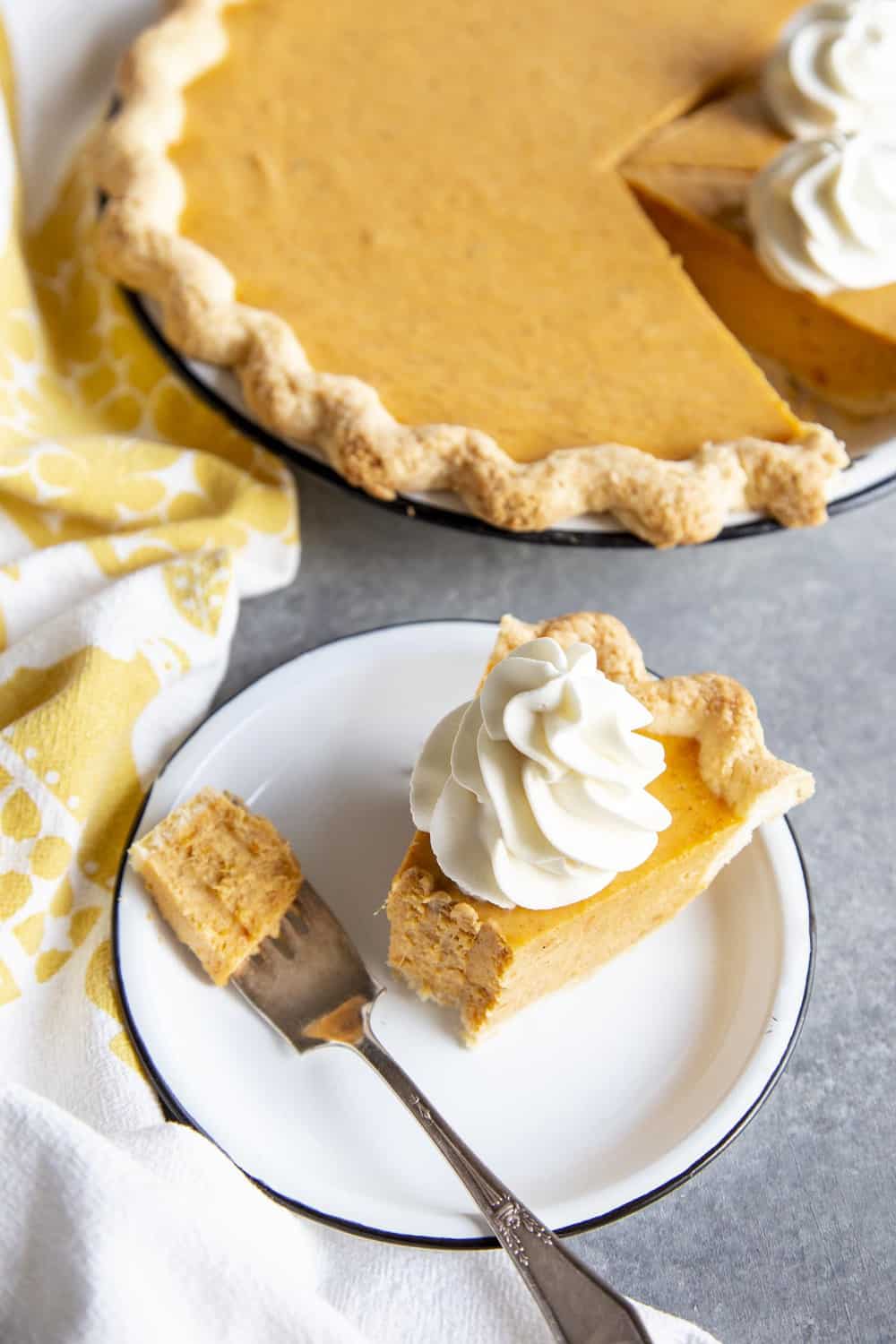 This Sweet Potato Pie is unlike any others you’ve eaten. The filling is made with cream cheese for a cheesecake like creaminess and texture you won’t be able to resist. Partial eaten slice of sweet potato pie on a plate next to the pie dish