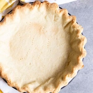 A par-bake pie crust on a gray surface next to a tea towel