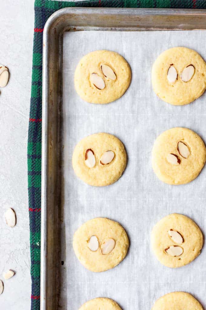 Almond Cookies areย ย buttery, soft and chewy these cookies are made with almond flour, almond extract, and topped with slices of toasted almond!ย Almond cookies on a baking sheet.