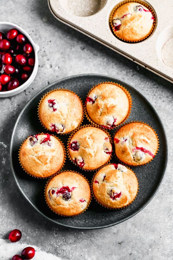 These Cranberry Muffins are the perfect blend of tart and sweet, light, fluffy and perfect for your morning breakfast. All you need is one bowl and 30 minutes to whip these babies up from start to finish. Cranberry muffins on a plate.