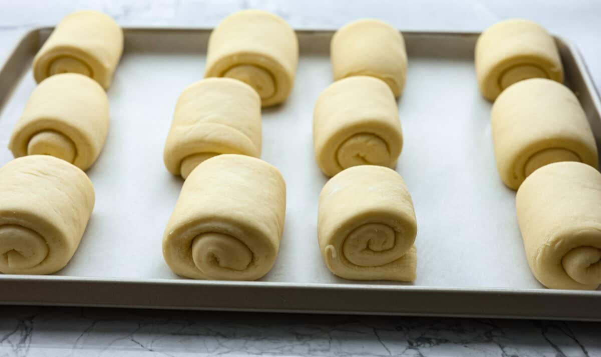 Lion House Rolls are the best dinner rolls for holiday meals or any occasion. These buttery, super-soft rolls are the perfect vehicle for soaking up delicious soups, sauces, and gravies. Angle shot of rolled dough on a baking sheet.