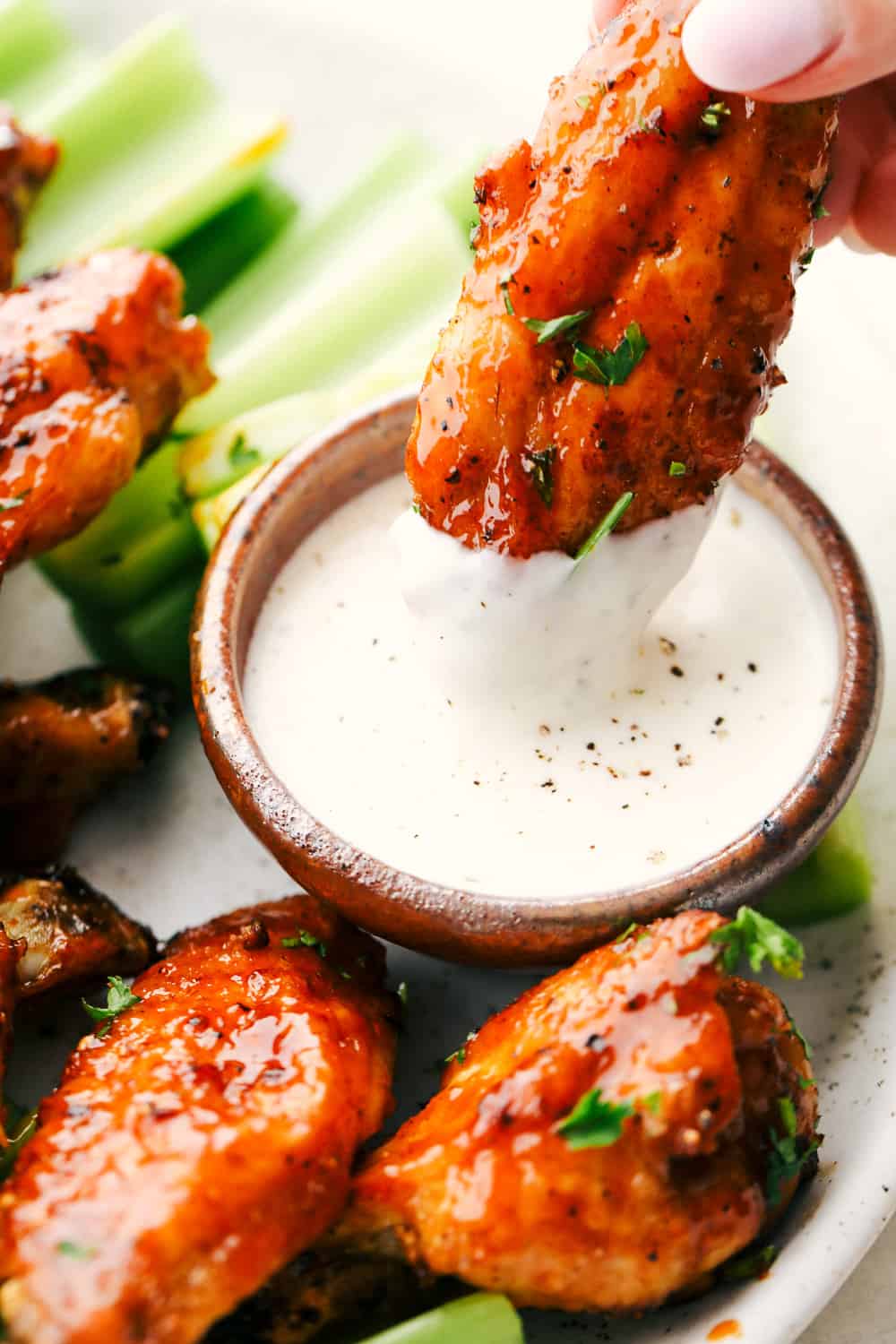 Crispy Air Fryer Chicken Wings are simply the best ever! Crispy on the outside, tender on the inside and with a smack of homemade buffalo sauce, they're finger lick'n good! Dipping a chicken wing in ranch sauce.
