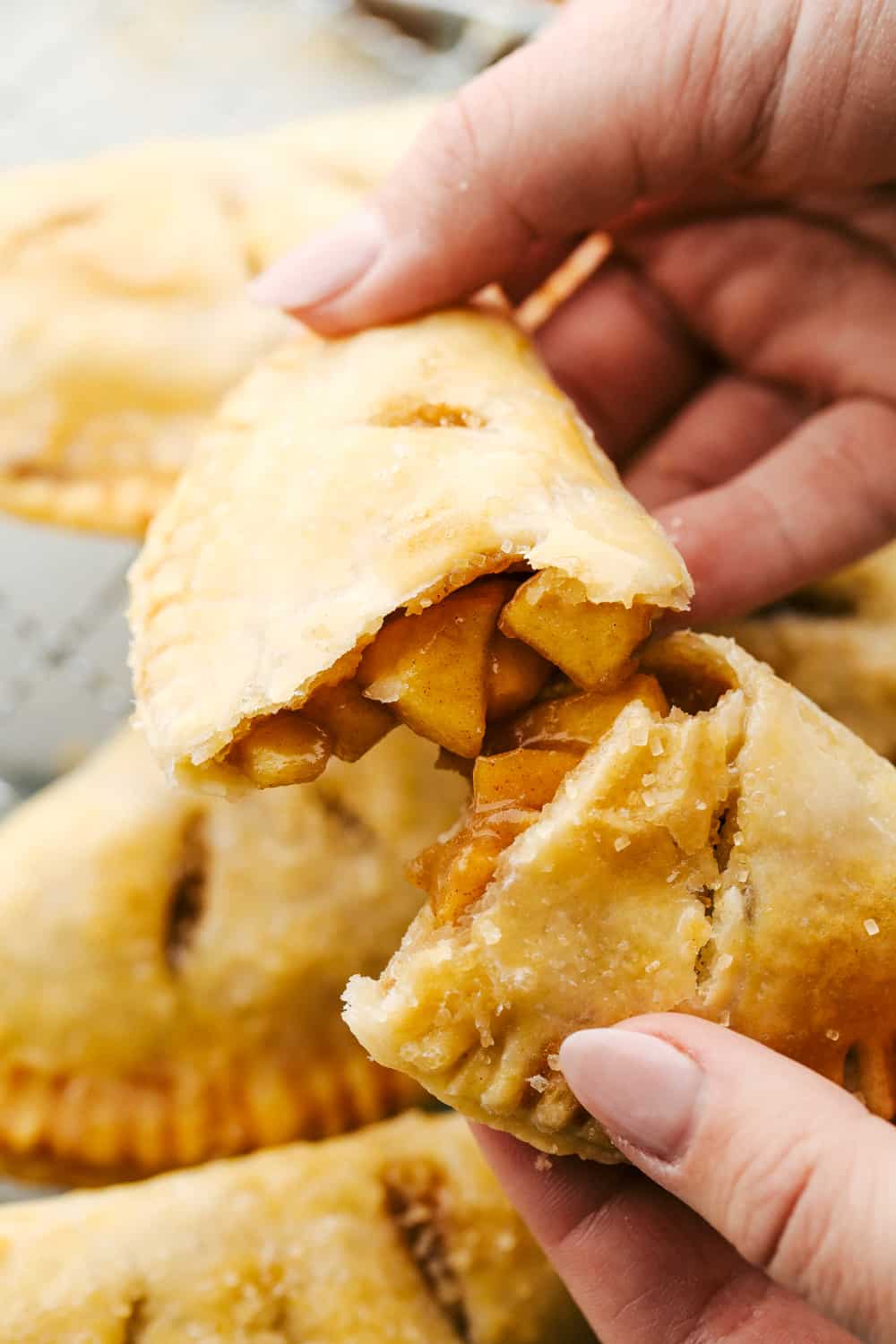 Seriously Amazing Air Fryer Hand Pies are an easy way to have dessert! Tender sweet spiced apples in a flakey crust you can hold in your hand! Breaking a hand held pie exposing the amazing filling.