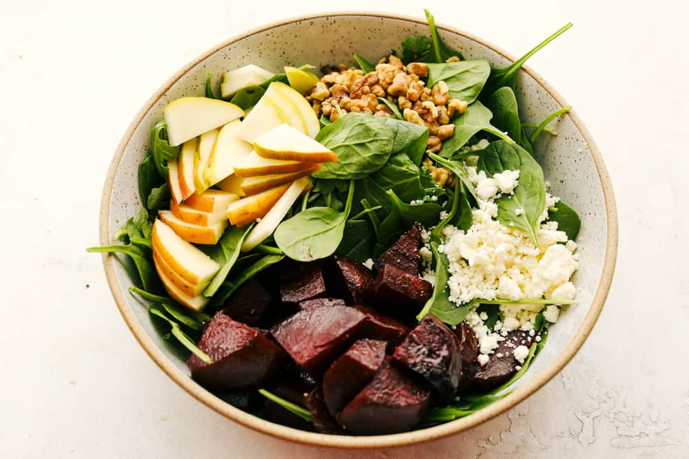 This Amazing Pear and Beet Salad is fresh, zingy, and absolutely delicious. It's a perfect combination of crisp-tender pears, sweet roasted beets, mixed greens all tossed in a honey vinaigrette. Pears, beets, spinach, feta and nuts in a bowl.