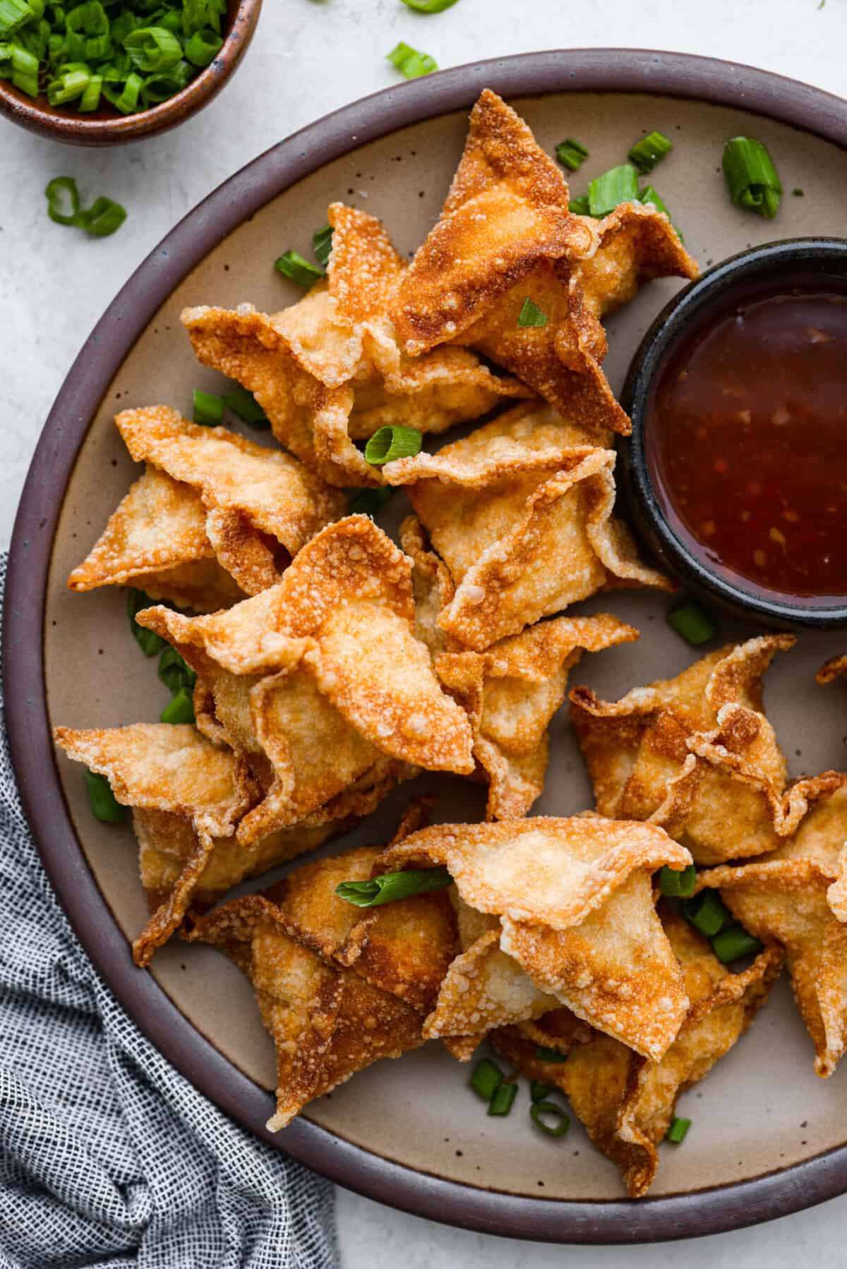 Crab Rangoons are a fun, Asian-inspired appetizer filled with crab meat, smooth cream cheese, and seasoning. Wrapped in a wonton wrapper and deep-fried, they are irresistible! Overhead shot of crab rangoon on a serving platter.