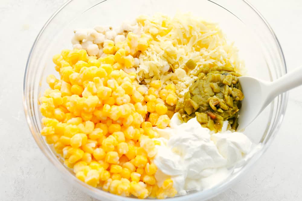 Easy, creamy and cheesy Hominy Casserole is a side dish that is sure to impress. This is not your average dish, it takes hominy to a whole new level. Ingredients for hominy casserole in a glass bowl.