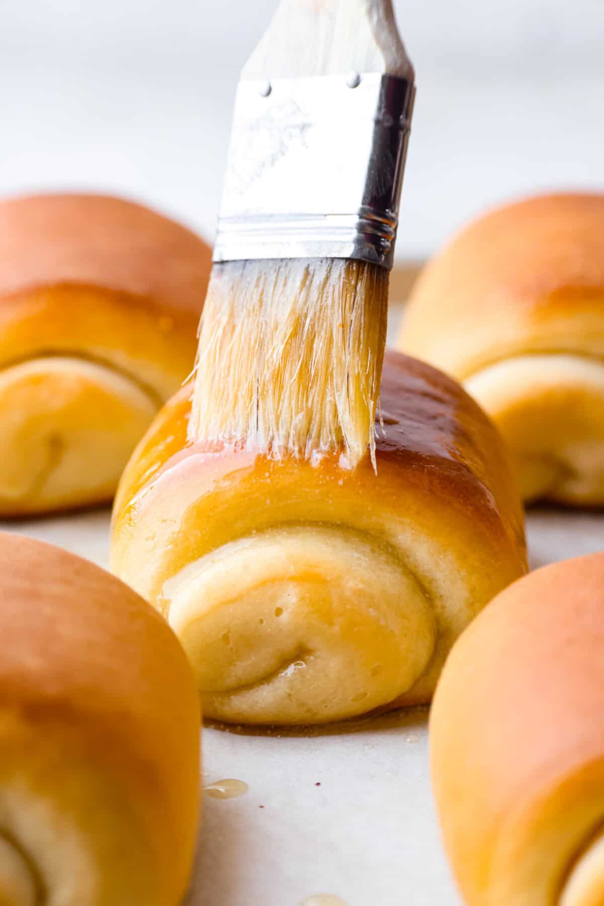 Lion House Rolls are the best dinner rolls for holiday meals or any occasion. These buttery, super-soft rolls are the perfect vehicle for soaking up delicious soups, sauces, and gravies. Close up shot of someone spreading butter on top of a lion house roll.