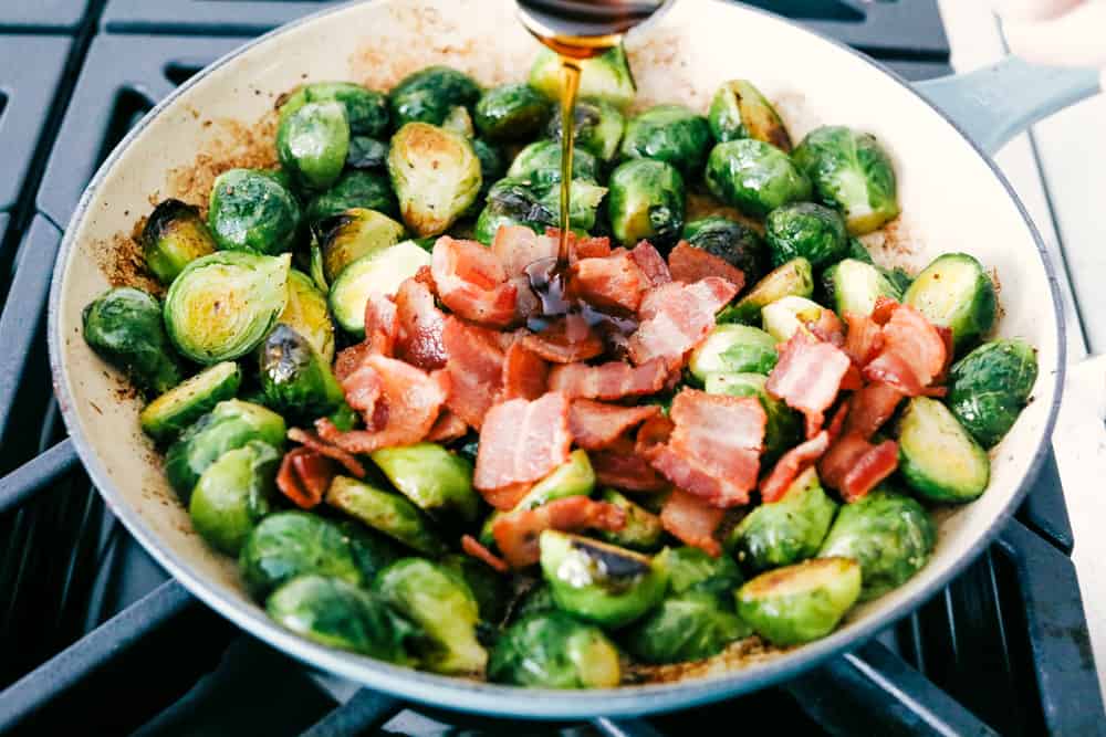 Perfect Sauteed Brussel Sprouts with Bacon is side dish supremacy. Crisp tender brussel sprouts tossed with crispy bacon and a drizzle of maple syrup is pure heaven. Pouring the maple syrup over the brussel sprouts and bacon.