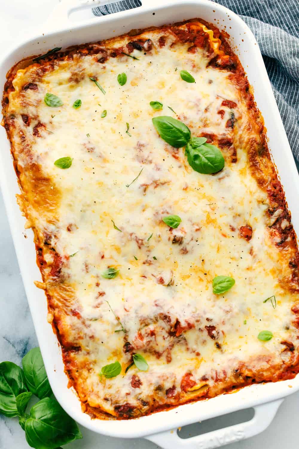 Full of flavor and hearty veggies, this truly is the Best Vegetarian Lasagna! Smothered in tender pasta, exquisite sauce and melty cheese this Lasagna is going to hit the spot! And I promise you won't miss the meat! Vegetable Lasagna in a white dish with basil on top.